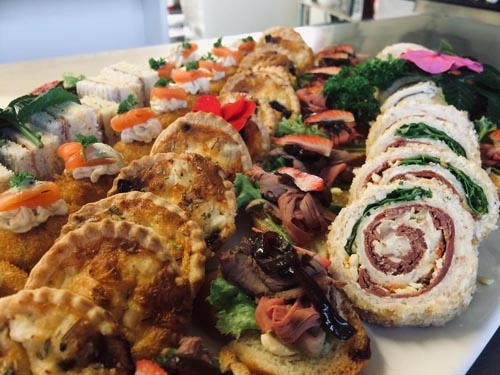 Close-up of assorted seafood platter with garnish, featuring rolls, herbs, and canapés—ideal for weddings or premium event catering