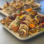 Assorted canapé party platter featuring bite-sized wraps, tarts, and savoury pastries, ideal for weddings or upscale event catering by Nikki.