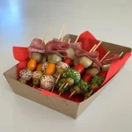 Box of assorted mini kebab skewers with meats, cheese, and vegetables, ideal for food-on-a-stick catering, events, or picnic platters