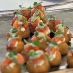 Tray of mini salmon herb bites with cream and garnish, ideal for canapé catering, weddings, or elegant events