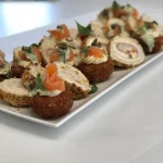 Plated salmon pinwheel canapés with herbs and garnish, perfect for elegant catering, receptions, or finger food events ideal for finger food catering at events, meetings, or parties